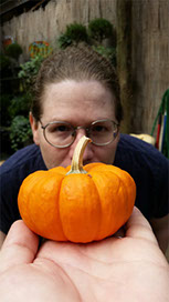 A photo of Erika over-looking a pumpkin.